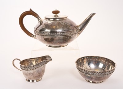 Lot 469 - George V silver three piece teaset in the Arts and Crafts style, comprising teapot of circular form, with overall planished decoration, fruitwood scroll handle and finial, engraved vine decorati...