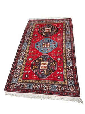 Lot 1503 - Caucasian rug, with three foliate medallions on brick red ground in multiple borders, with tassel ends, 225 x 130cm