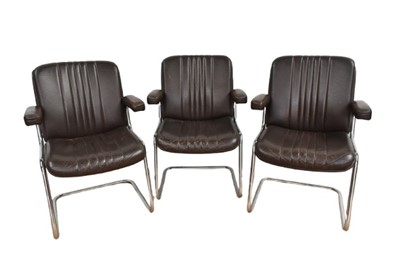 Lot 1334 - Set of three vintage chromed and leather upholstered elbow chairs.