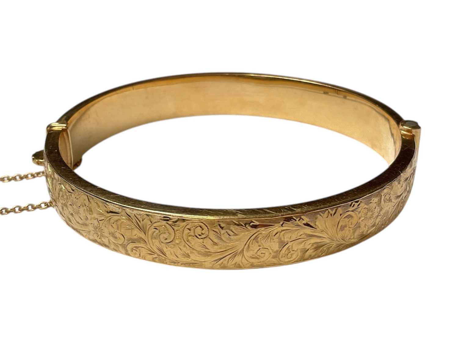 Lot 59 - 18ct gold hinged bangle with engraved floral scroll decoration to one side (Birmingham 1962)