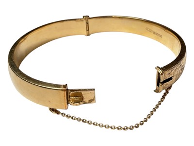 Lot 59 - 18ct gold hinged bangle with engraved floral scroll decoration to one side (Birmingham 1962)