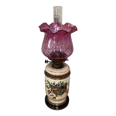 Lot 5039 - Victorian ceramic oil lamp with printed and coloured decoration, with a moulded cranberry glass shade