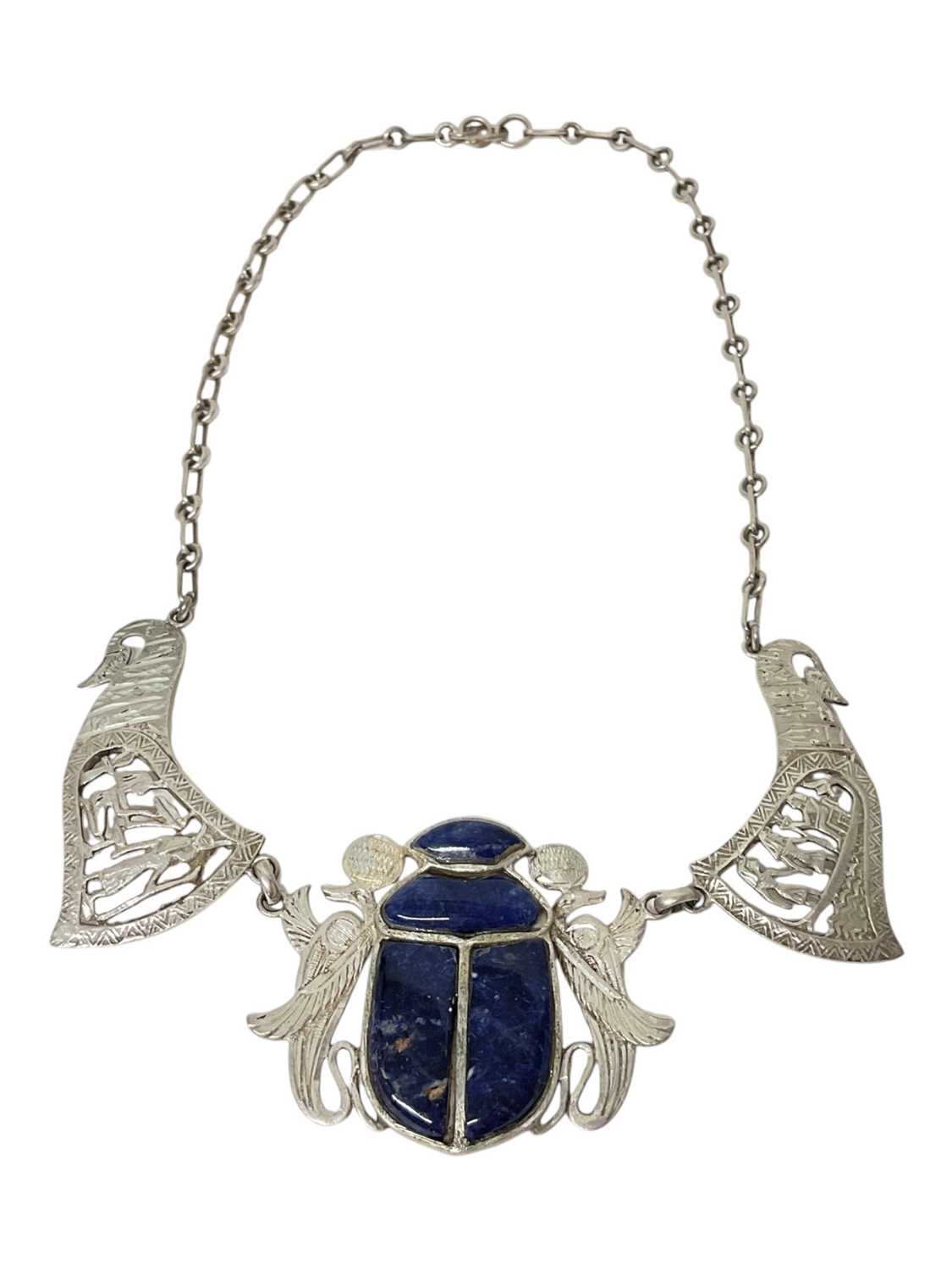 Lot 14 - Egyptian white metal and blue stone scarab beetle pendant necklace with pierced and carved white metal panels depicting birds and Egyptian figures