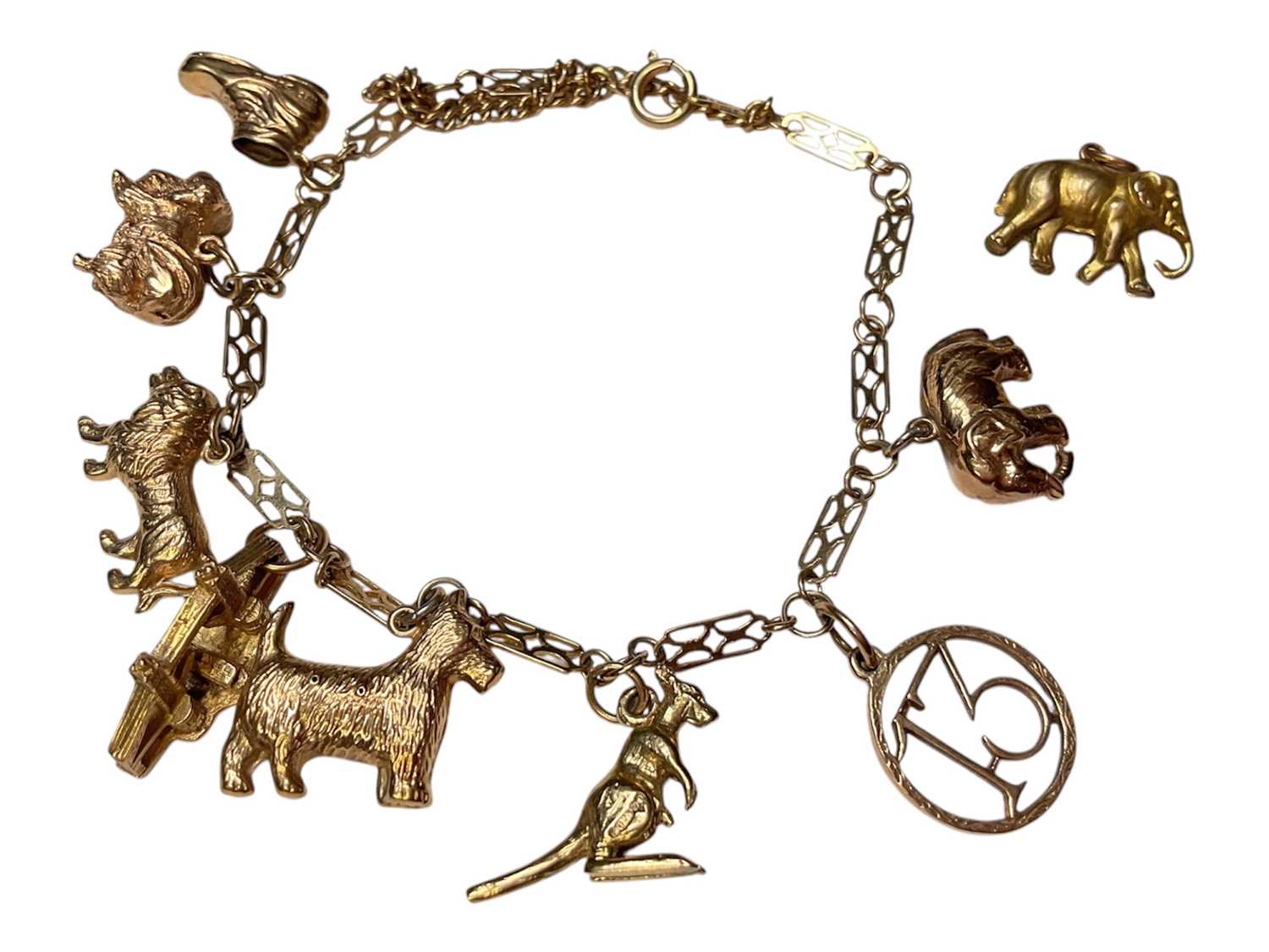 Lot 21 - 9ct gold fancy link charm bracelet with eight 9ct gold novelty charms and a loose gilt metal elephant charm