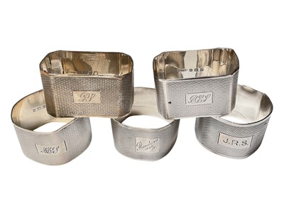 Lot 129 - Five various silver napkins rings with engine turned decoration and engraved initials/names
