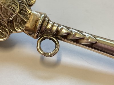 Lot 134 - Silver baby rattle with cupid head and wings decoration, 12cm, together with a silver mounted miniature prayer book decorated with Reynold's Angels (2)