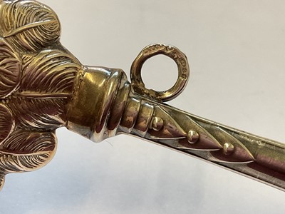 Lot 134 - Silver baby rattle with cupid head and wings decoration, 12cm, together with a silver mounted miniature prayer book decorated with Reynold's Angels (2)