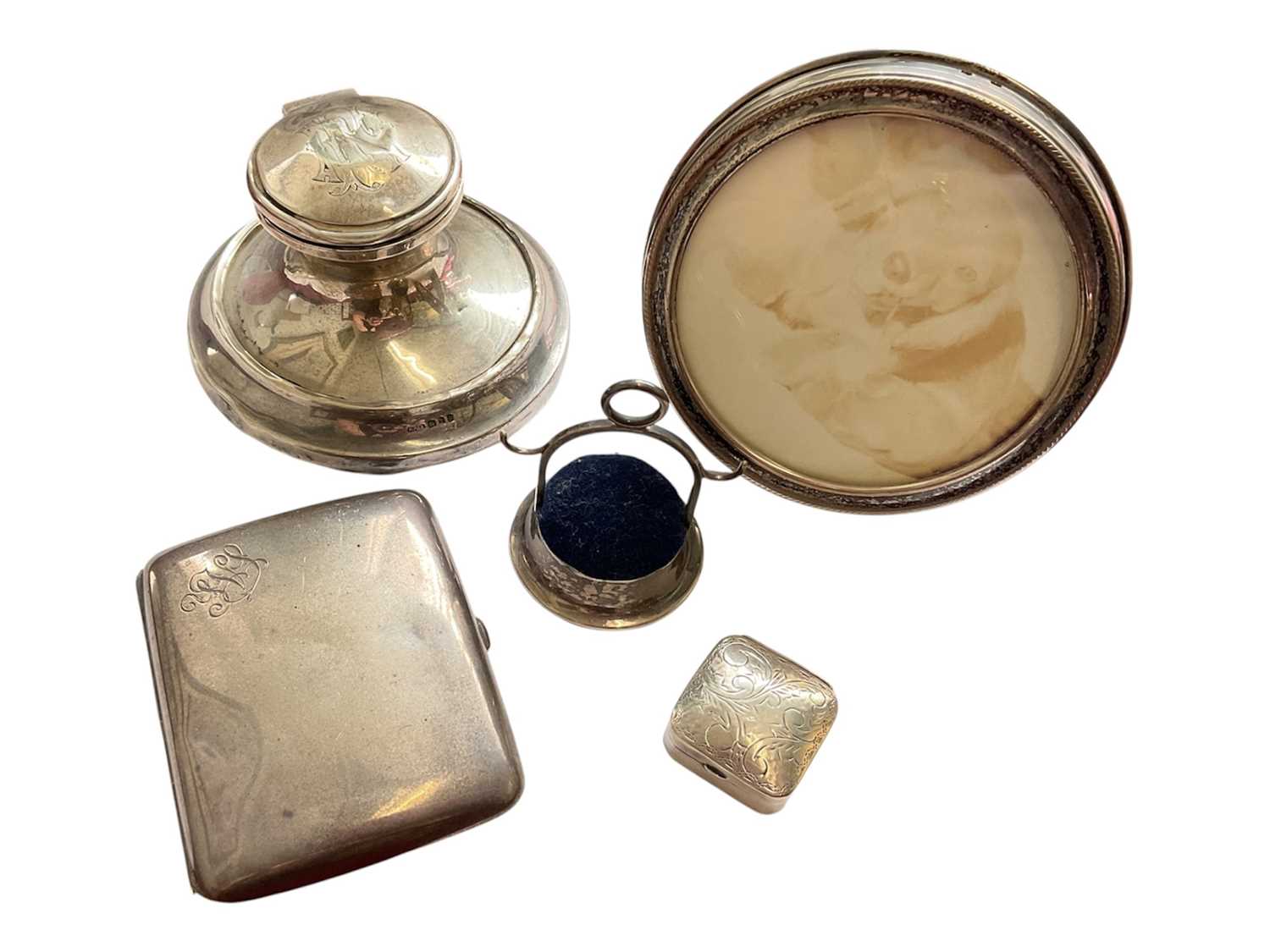 Lot 83 - Victorian silver desk inkwell, Edwardian silver cigarette case, silver mounted pin cushion, silver circular photograph frame and a silver 925 pill box (5)