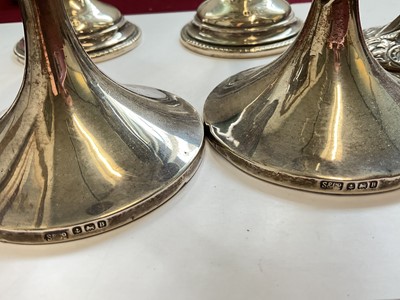 Lot 84 - Pair of late Victorian silver spill vases with embossed foliate scroll decoration, another pair of silver spill vases and a pair for silver candlesticks