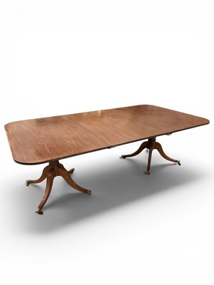 Lot 1411 - Regency mahogany twin pedestal dining table, the rectangular top raised on ring turned columns and splayed reeded legs, terminating in brass cappings and castors, with one additional leaf, 123cm...