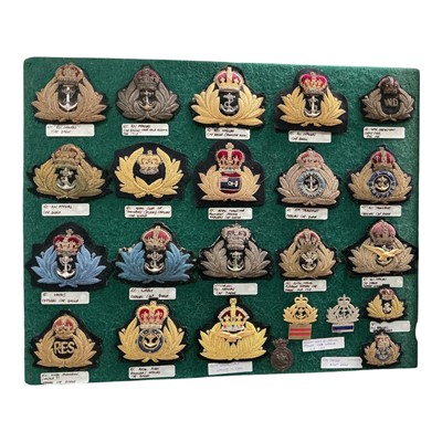 Lot 722 - Collection of twenty three Victorian and later Royal Navy badges, mounted on a baize board, (23).