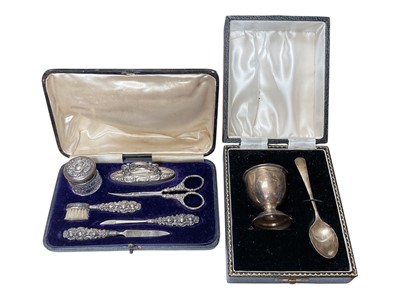 Lot 180 - Edwardian silver mounted manicure set in a velvet lined fitted case, together with an Elizabeth II silver egg cup and spoon in a fitted case (Birmingham 1963)