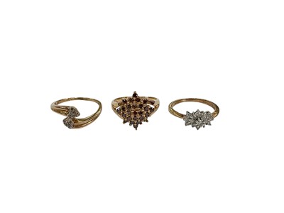 Lot 215 - Three 9ct gold diamond cluster rings to include a cross-over ring with heart shaped diamond set terminals, size M, cinnamon diamond cluster ring, size L and one other diamond cluster ring, size...