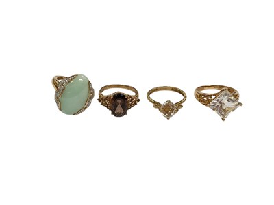 Lot 219 - Four 9ct gold gem set dress rings to include an oval jade / green hardstone and diamond ring, smoky quartz ring, synthetic white single stone ring and a clear faceted bead ring, all size M