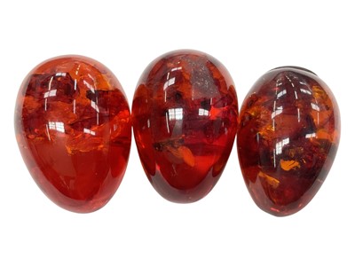 Lot 938 - Three reconstituted amber polished eggs, one with a yellow metal pendant mount marked 9ct
