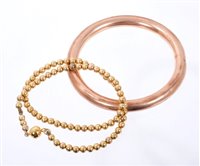 Lot 422 - Yellow metal slave bangle and a similar bead...