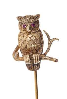 Lot 557 - Novelty gold stick pin in the form of an owl with ruby eyes and engraved gold feathers, perched on a rustic gold branch