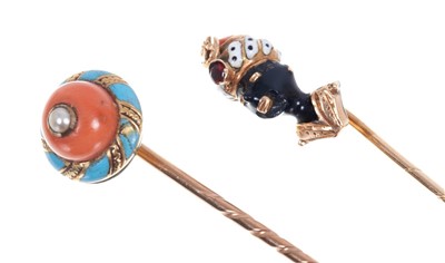 Lot 559 - Antique novelty stick pin in the form of a Blackamoor, with coral, enamel and gem set headdress, together with a Victorian coral and enamel stick pin (2)