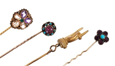 Lot 560 - Four Regency / early Victorian stick pins – to include a gold cannetille work flower-head stick pin set with emerald, amethysts and topaz, a Regency garnet and turquoise forget-me-not stick pin and...