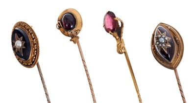 Lot 564 - Four Victorian stick pins – to include a Victorian cabochon garnet and seed pearl stick pin, cabochon garnet and gold garter stick pin, garnet and gold eagle claw stick pin and one other