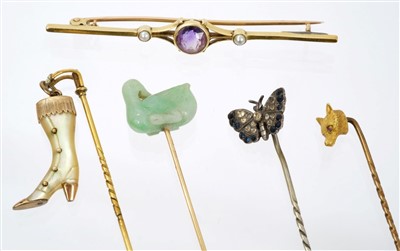 Lot 566 - Four antique stick pins – to include a carved green hardstone / jade duck stick pin, together with an Edwardian 15ct gold and amethyst bar brooch (5)