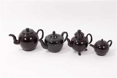 Lot 114 - Four 18th century Jackfield brown glazed pottery small teapots -one with cooked handle and raised on legs (4)