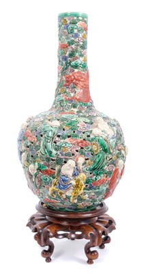 Lot 39 - Chinese famille verte reticulated bottle vase, decorated in relief with immortals and a dragon, six character seal mark to base, with a carved hardwood stand, vase measures 35cm height