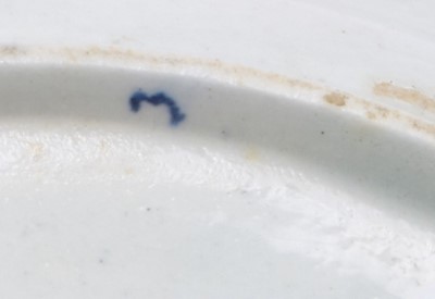 Lot 50 - A good Lowestoft blue and white plate c.1770, painted with a Chinese lady holding a parasol, standing before a zigzag fence, the rim with three vignettes of prunus issuing from rockwork, 23cm