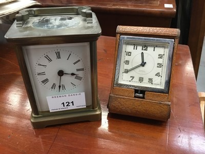 Lot 121 - Brass carriage clock with white enamel dial, together with a brown leather cased travelling clock (2)