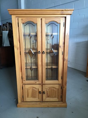 Lot 22 - Contemporary stained pine bookcase with two leaded glazed doors above enclosing three fixed shelves and two panelled doors below H180cm W104cm D37cm