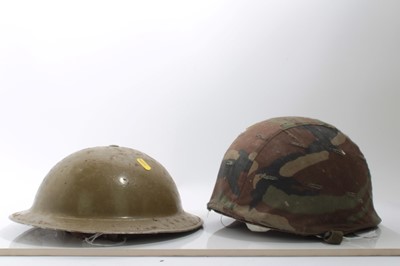 Lot 697 - Second World War British Army helmet, in sand coloured camouflage finish, with naming under brim, together with an American helmet with camouflage cover (2)