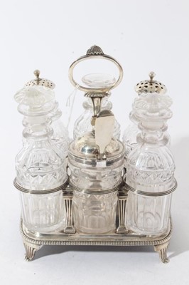 Lot 64 - George III silver cruet frame of rectangular form with reeded decoration and central handle, on four fluted feet, with six matching cut glass condiment bottles, including three with silver mounts.