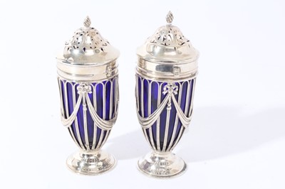 Lot 112 - Edwardian silver sugar caster of tapered cylindrical form, wire frame body with ribbons and swags and blue glass liner, pierced cover with bayonet fitting, on circular foot, (London 1902)