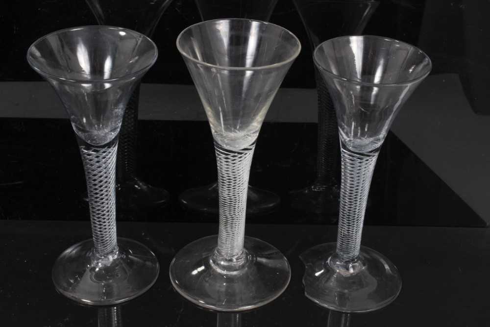 Lot 152 - Three Georgian wine glasses, c.1750, all with drawn trumpet bowls on multi-spiral air twist stems, 16cm to 16.75cm height