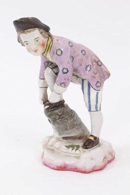 Lot 102 - 19th century French faience figure of a boy tying his shoelaces, wearing tricorn hat, lilac floral jacket, yellow shirt, and blue and white striped breeches, mark on the base for Theodore Deck, 16....