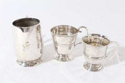 Lot 133 - George V silver christening mug of tapered form with central reeded band, with scroll handle, on a circular foot, (Birmingham 1935), together with two other silver christening mugs (various dates a...