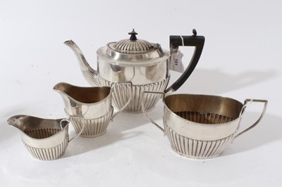 Lot 151 - George V silver four piece tea set, comprising teapot of half fluted form, with angular ebony handle and hinged domed and fluted cover, with carved ebony finial, on an oval base, matching sugar an...