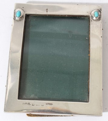 Lot 198 - Edwardian Arts & Crafts silver photograph frame of rectangular form, set with two cabochon turquoise stones, (Birmingham 1904), maker Liberty & Co, also stamped Cymric, with leather easel back, 11...
