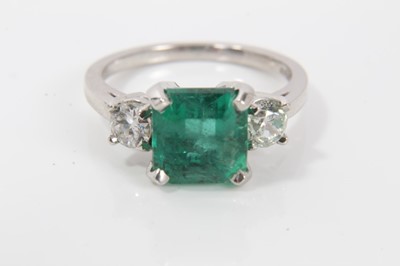 Lot 237 - Emerald and diamond three stone ring with a square step-cut emerald measuring approximately 7.50mm x 7.25mm x 5.25mm, estimated to weigh approximately 1.90cts, flanked by two old cut diamonds in cl...
