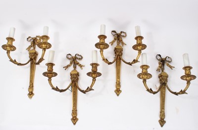 Lot 308 - Set of four brass two branch wall lights with ribbon and lion mask decoration