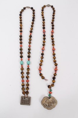 Lot 8 - Two Chinese tiger's eye and coral bead necklaces with white metal panel pendants