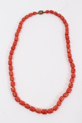 Lot 46 - Old Chinese coral necklace with barrel shaped polished beads and oval silver gilt clasp with wire work flower decoration, 63cm long