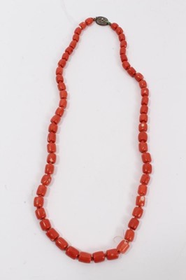Lot 48 - Old Chinese coral necklace with barrel shaped polished beads and oval silver clasp with wire work flower decoration, 65cm long