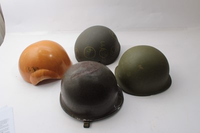 Lot 263 - American M1 Steel helmet reworked for the Korean War, together with another M1 steel helmet and two helmet shells (4)
