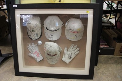 Lot 2055 - Group of four signed golf caps, two signed golf gloves and a signed golf ball, all mounted in a glazed frame, 78 x 70cm