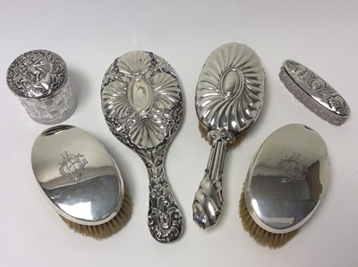 Lot 159 - Victorian silver backed hand mirror with ornate embossed decoration (Birmingham 1876), together with three silver backed brushes and two silver silver topped