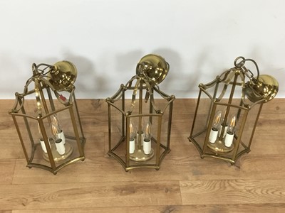Lot 822 - Set of three Georgian style brass hanging hall lanterns, each of hexagonal form with bowed glass housing three lights, total height 41cm