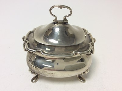 Lot 190 - George V silver tea caddy of cauldron form with twin ring handles, hinged cover with folding handle and gilded interior, raised on four hoof feet, (London 1917), maker Goldsmiths & Silversmiths Com...