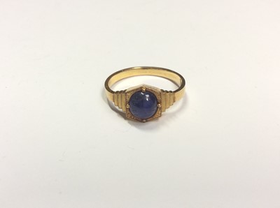 Lot 508 - Art Deco yellow metal oval blue cabochon sapphire ring in four claw setting with stepped cut shoulders. Possibly Indian gold. Ring size L½
