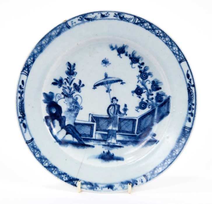Lot 28 - Lowestoft plate, painted in blue with a Chinese lady by a zig-zag fence and a large vase of flowers, with a diaper and half-flowerhead border, 22.3cm diameter